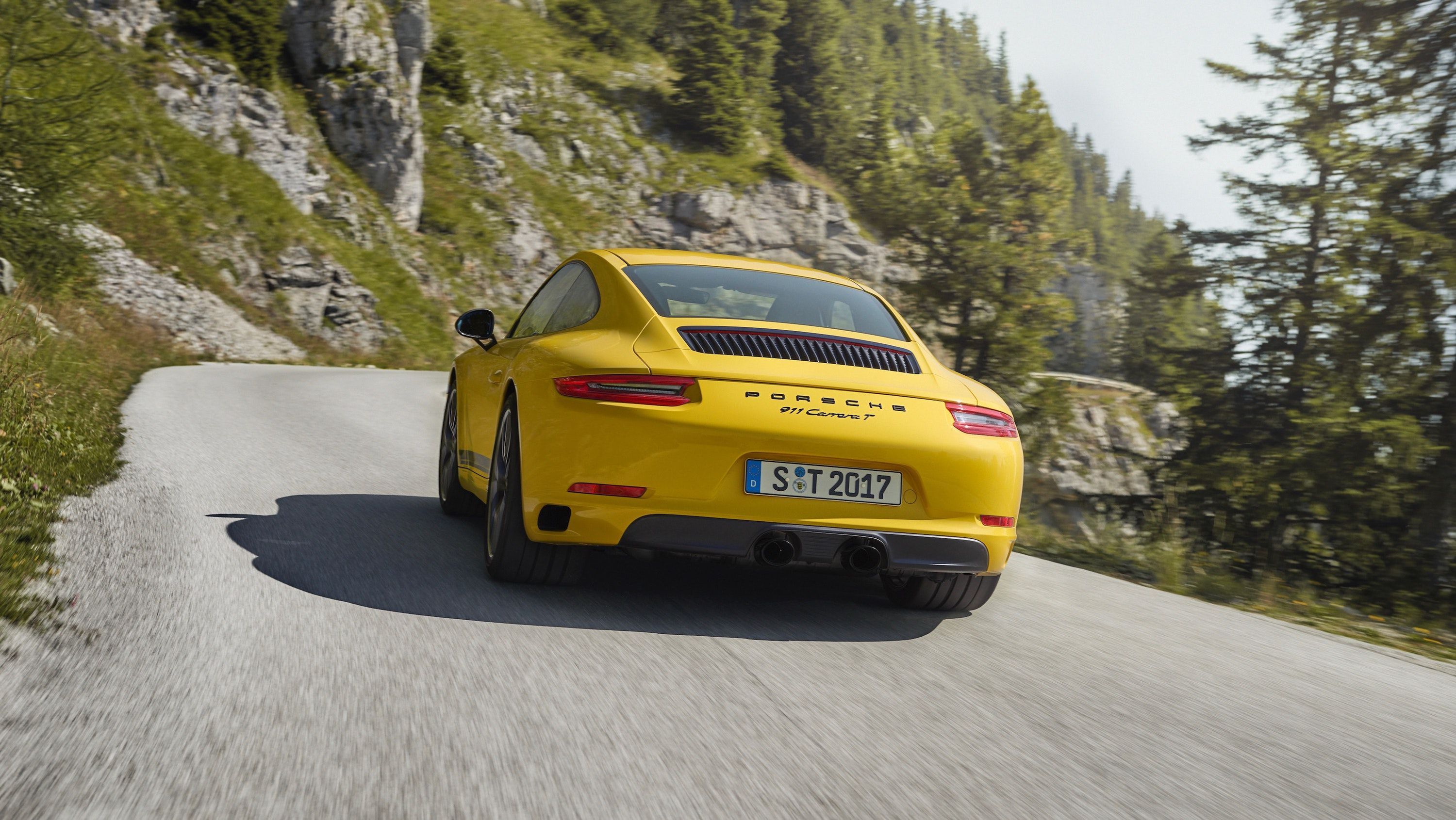 Yellow Porsche 991 rear view driving on a road up a mountain